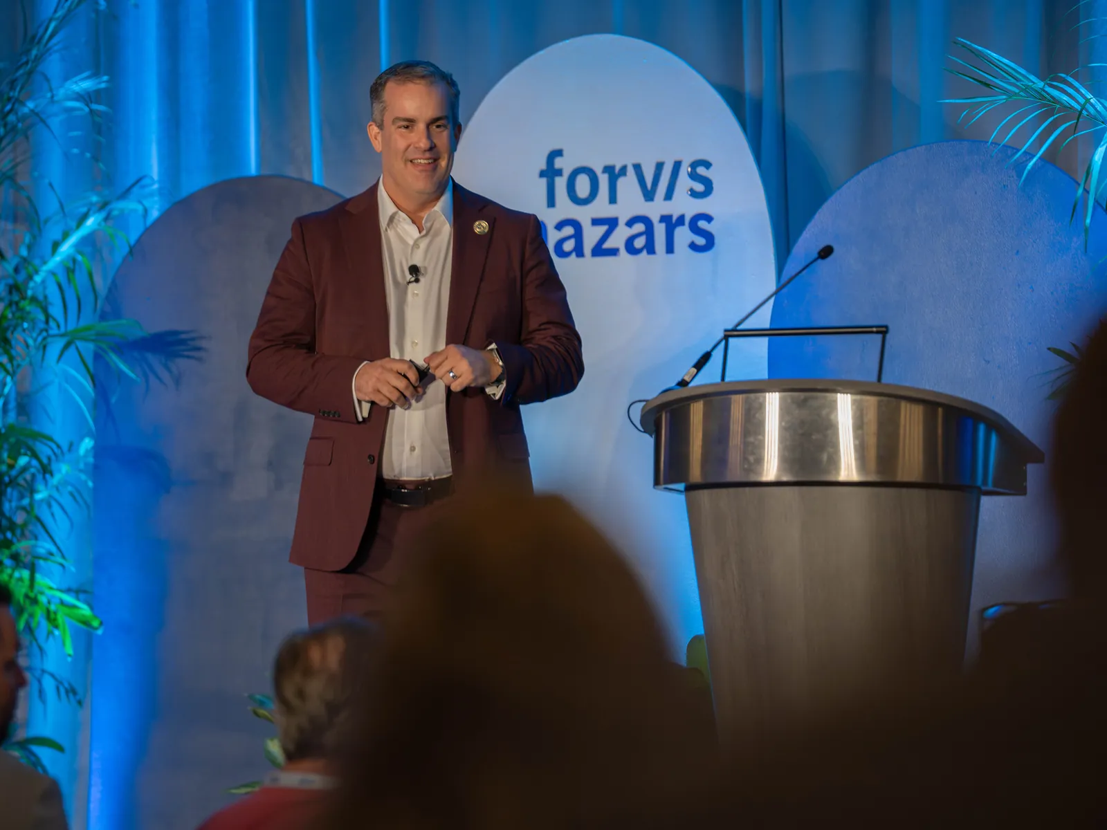 James Benham on stage delivering a keynote in front of the Forvis Mazars logo